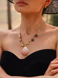 Detail of a gold ocean necklace with turtle and shell charms worn by a model