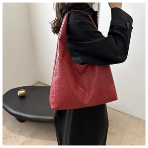 Detail of red woven tote bag styled as an underarm shoulder bag on a female model