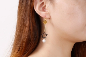 Gros plan de boucles d'oreilles pendantes avec étoile noire et perle sur un mannequin