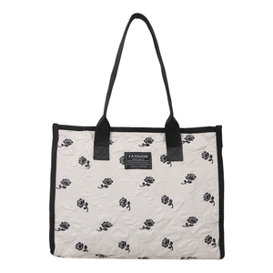 Sac cabas matelassé blanc avec broderie de rose noire et anses sur fond uni blanc