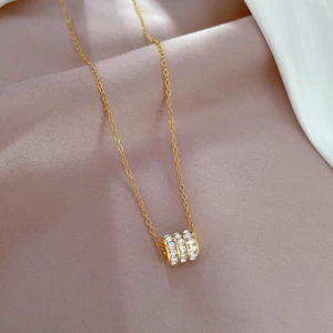 Macro shot of gold cylinder pendant with triple rows of white zircons on silk background
