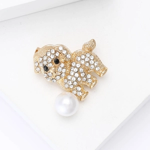 Detail of a golden dog brooch with sparkling rhinestones and a white pearl accent