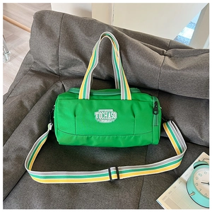 Detail view of a green cylinder sports bag with striped handles on a sofa