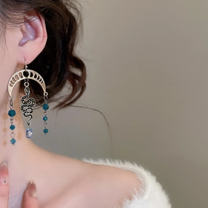 Detail view of vintage snake moon earrings with blue beads and crystal tassels on model