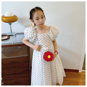 Close-up of a red flower-shaped crossbody bag with a white polka dot dress