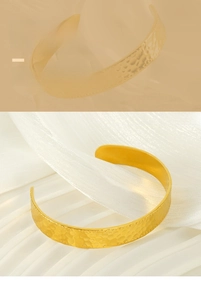 Détail du bracelet ouvert en acier doré avec texture martelée sur tissu de soie