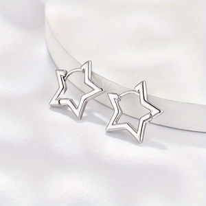 Minimalist silver star earrings with polished hollow design on a white satin stand