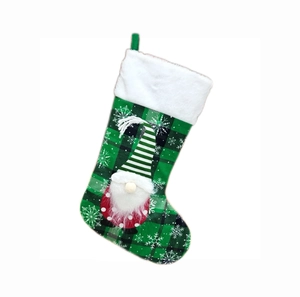 Close-up of green plaid Christmas stocking with a plush gnome and white snowflake patterns