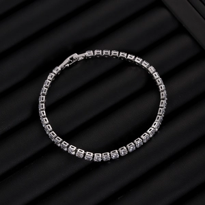 Macro shot of silver-tone tennis bracelet with clear zircon stones on black display pad