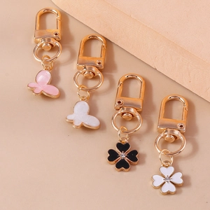 Detail of butterfly and four-leaf clover keychain charms with enamel and gold finish