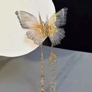 Detail of ethereal butterfly hair clip with mesh wings, gold metal and long tassel chains