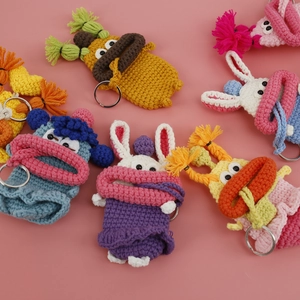 Handmade crochet cartoon key covers in colorful animal designs on a pink background