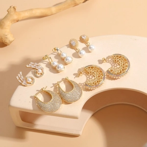 Elegant 14K gold plated pearl and zircon earring set displayed on geometric pedestals