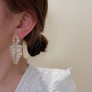 Detail of geometric tassel earrings with full diamonds and gold dangling fringe style