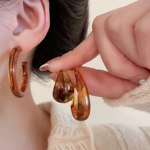 Detail view of amber tortoiseshell acrylic earrings in round and teardrop shapes