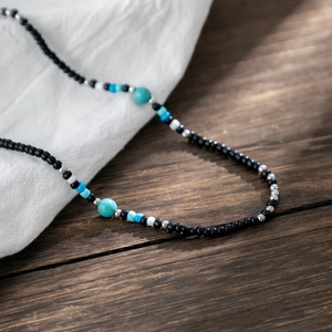 Handmade beaded necklace with turquoise stones and mixed seed beads on wood background