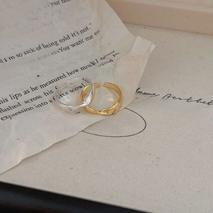 Minimalist irregular wavy open rings in gold and silver finish on vintage newspaper background