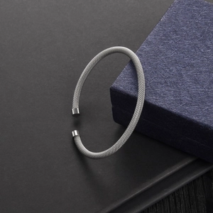 Detailed close-up of a silver mesh cable braided open cuff bracelet on a gift box