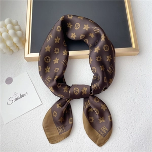 Detailed view of dark brown silk scarf with gold flower motifs and MY monogram patterns