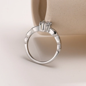Detail shot of a wave-edged stainless steel ring featuring a clear zircon stone setting