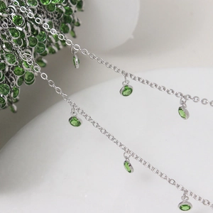 Macro view of silver plated chain featuring round green rhinestone pendant charms