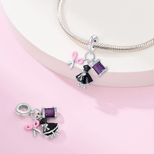 Macro view of S925 silver charms featuring pink scissors, black dress and thread spool
