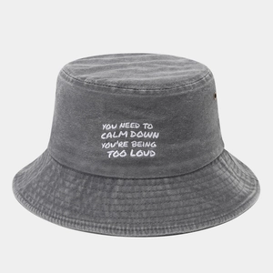 Close-up of embroidered text on washed grey cotton bucket hat with parallel stitched brim