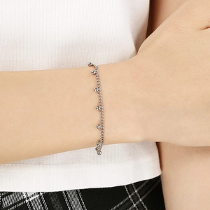 Close-up of a silver bead charm bracelet on a wrist showing the fine chain detail