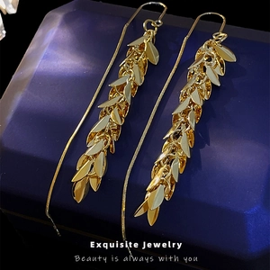Elegant gold leaf tassel earrings in a dark blue velvet jewelry box with metallic finish