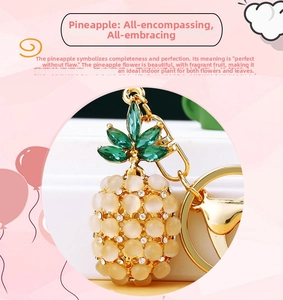 Detail of pineapple keychain featuring opal beads and green leaves on gold plating