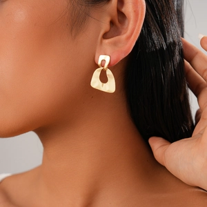Detail of gold-colored irregular geometric teardrop earring worn by a model