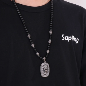 Detail of men's black beaded necklace featuring vintage lion head pendant on black tee