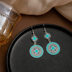 Detail of bohemian drop earrings with turquoise sunflower pattern on black display
