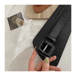 Close-up of black crocodile-embossed wide waist belt with a square metallic buckle