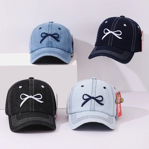 Close-up of children's denim baseball caps showing bow embroidery and washed texture