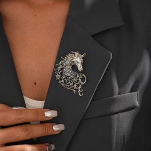 Detailed view of a vintage silver horse brooch with colorful rhinestones on a black suit lapel