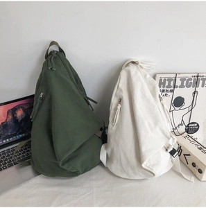 Detailed close-up of army green and cream canvas backpacks with zipper and buckle hardware