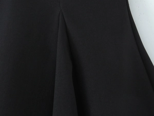 Detail shot of the black twill fabric texture and layered pleats on this vintage dress