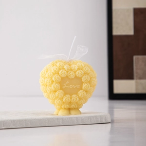 Detail of yellow heart-shaped rose candle with Love engraving and silk ribbon
