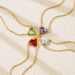 Detail of heart-shaped crystal pendant necklaces in green, purple, red, and white on gold chains