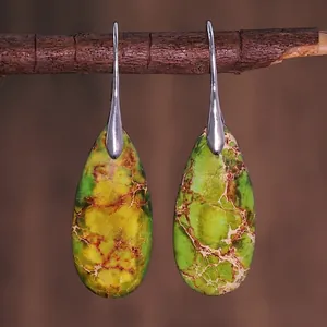 Detail of vintage teardrop earrings with green and yellow emperor stone texture