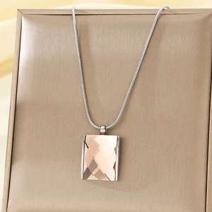 Detail of square champagne glass pendant on silver snake chain over golden luxury box