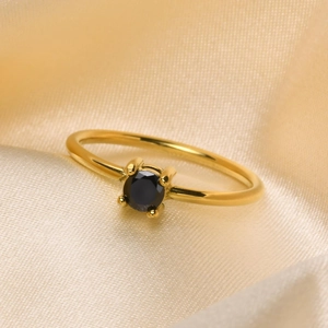 Adjustable gold titanium ring featuring a black zircon stone on champagne silk background