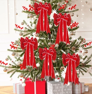 Close-up of five red Christmas bows with plush edges hanging on a tree with gift boxes