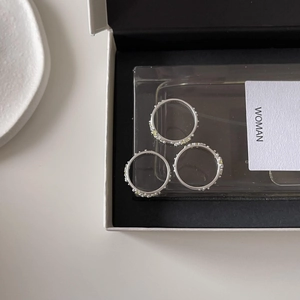 Detailed top view of three minimalist silver rings with yellow gemstones in a black box
