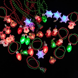 Dettaglio di collane natalizie luminose con Babbo Natale e renne su sfondo scuro