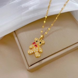 Detail of bear pendant with sparkling crystals and red hearts on a gold chain