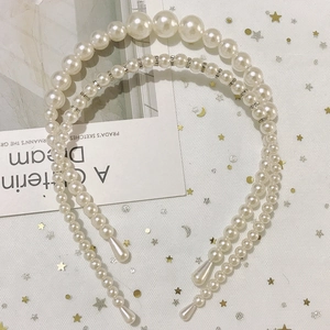 Detail of handmade pearl headbands with rhinestone accents on a soft mesh fabric background