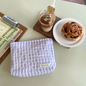 Detail of lavender checkered fabric makeup bag with textured seersucker finish and woven label