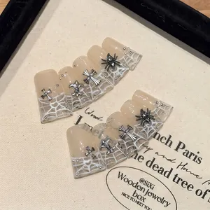 Gothic press-on nails with silver cross and spider charms on nude spiderweb base